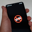 Man holding phone that shows the word "VPN" crossed out because it's been banned.