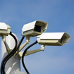 Three surveillance cameras on an outdoor post.