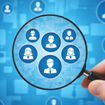 A hand holding a magnifying glass over blue digital user profiles