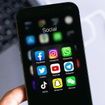 Phone screen open to a social media folder with familiar apps like Facebook and Instagram.