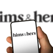 Phone screen with Hims & Hers logo in front of a blurry screen.