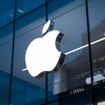 The Apple logo is prominently displayed on the exterior of a modern glass building.