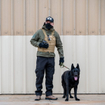 n Immigration and Customs Enforcement (ICE) officer and a black German Shepherd conduct surveillance.