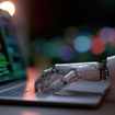 Robotic hand typing on laptop displaying code.