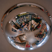 Two people stand under retail surveillance mirror.