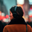 Woman wearing headphones in city at night.