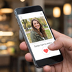 Close-up of a hand holding a smartphone displaying a dating app profile with a smiling woman and a 'Swipe right to match' button in a cafe setting.