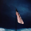 A drooping American flag amid a dark sky.