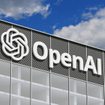 OpenAI logo on a gray corporate building against a blue sky