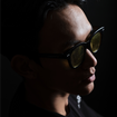 Moody fashion portrait of a man in sunglasses on a dark background.
