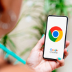 Woman with blue nails holding smartphone displaying Google Chrome logo