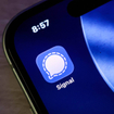 Closeup of the signal messaging app icon on a smartphone screen, displaying the iconic white speech bubble logo against a blue background