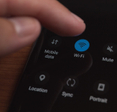 A close-up photo of a man&#x27;s fingers touching the Wi-Fi button on his cell phone.