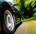 A close-up of the front of a black sports car as it speeds past, signifying increased internet speeds.