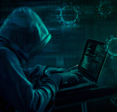 A hooded hacker on their laptop, sending out an online pandemic scam.