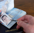 A close-up of a man&#x27;s hands fording a US passport, which can be a type of synthetic identity theft.