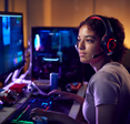 A young woman is playing a video game on her desktop computer.