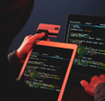 A hooded internet criminal is hacking a laptop in the dark and stealing credit card details.