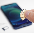 fingers holding several sim cards blurry phone in the back
