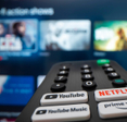 Remote control with button for youtube and other streaming services in the back blurred TV with videos to choose from