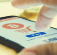 A close-up of a finger tapping a button to pay with bitcoin. Crypto is an anonymous payment method you can use to buy a VPN.