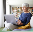 Senior woman using credit card while doing online shopping on laptop at home
