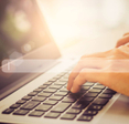 A pair of hands typing on a laptop with an abstract search bar in the foreground.
