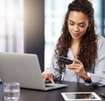 A woman online shopping on her laptop while holding her credit card.