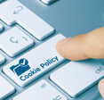 A finger shown pressing a button on a keyboard that says &quot;Cookie Policy.&quot;