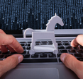 Person with Trojan horse icon on laptop affected by virus.