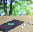 A smartphone displaying the Spotify app next to wireless buds