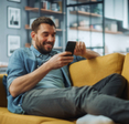 Man on couch smiling at phone