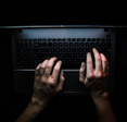 Hands on laptop in dark room