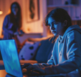 Girl looking worried at her laptop while mom watches in the distance
