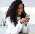 Woman uses a smartphone in her kitchen.