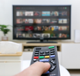 A remote is pointed toward a TV with Netflix on.