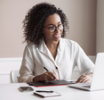 Woman holds a pen while staring at her laptop.