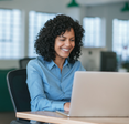 Woman smiles while staring down at her laptop.