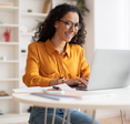 Woman smiles and types on her laptop in her office.
