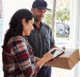 A woman signs for a package in her doorway.