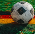 Soccer ball on field atop grass painted like German flag for UEFA EURO 2024
