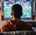 A man sits in front of the TV, watching sports. 