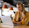 A woman sits at a desk and types on a laptop. 