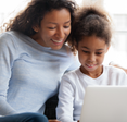 A mom and daughter sit together using a laptop.