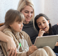 A mom and her two kids use an iPad together.