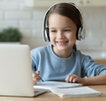 A child wears headphones while using a computer. 