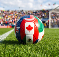 Football world cup soccer ball decorated with flags of 2026 hosts on green soccer field