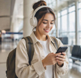 Female traveler in airport terminal using smartphone