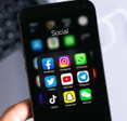Phone screen open to a social media folder with familiar apps like Facebook and Instagram.