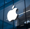 The Apple logo is prominently displayed on the exterior of a modern glass building.